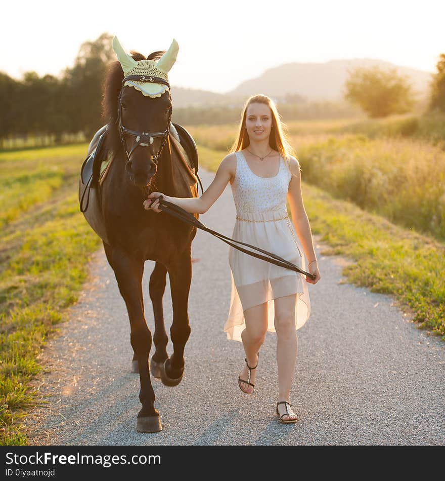 Beautiful young woman with horse outdoor on a walk in nature.