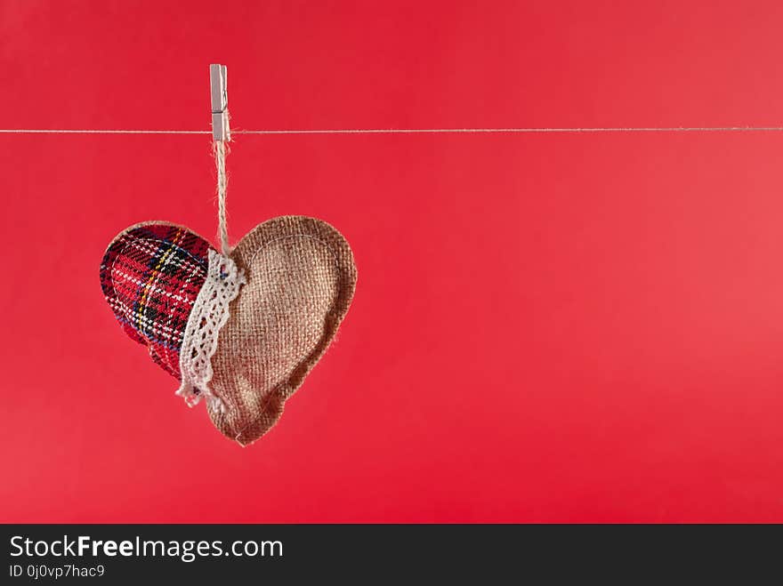 Heart hangs on rope isolated on red background and space for text