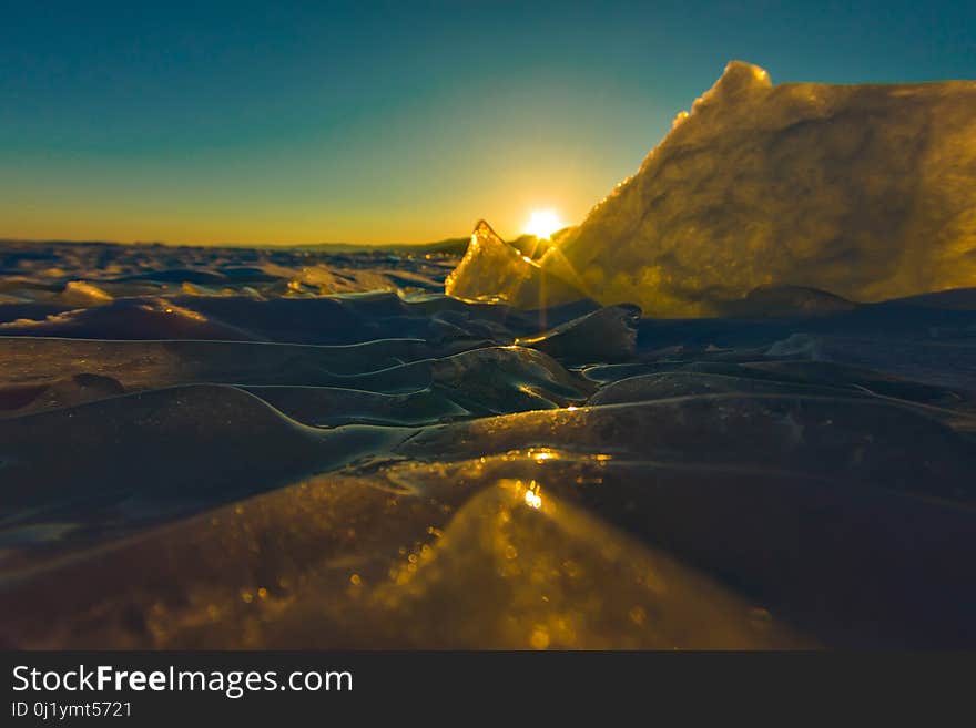 Pure transparent ice of Lake Baikal through the sun is shining in the sunset.