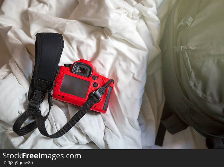 Camera and bag on a bed in the morning.