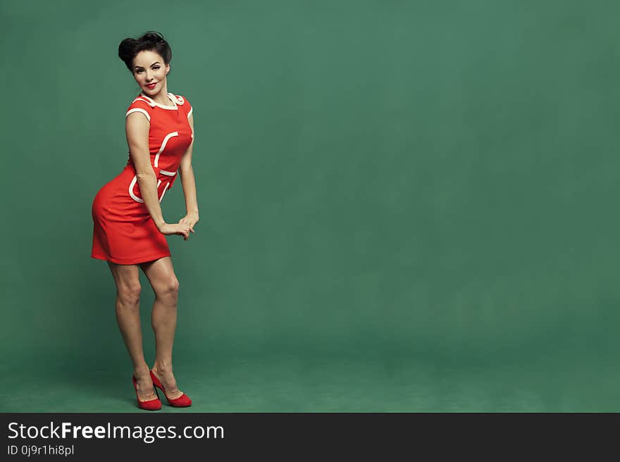 In red dress on green background girl in vintage style. beautiful girl in full growth