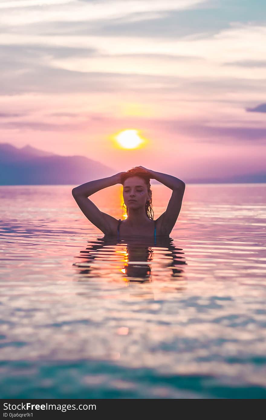 Selective Focus Photo of a Woman Bathing in Body of Water during Golden Hour