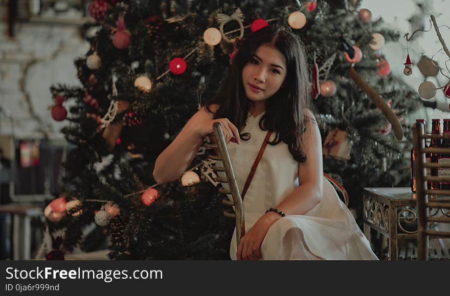 Woman in White Sleeveless Dress Sitting on Dining Chair