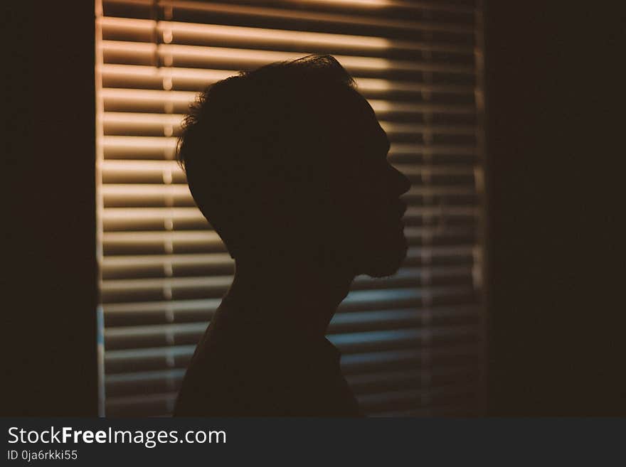 Man&#x27;s Silhouette Near White Window Blinds