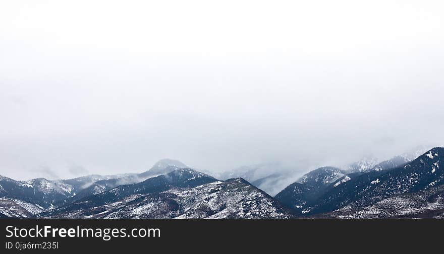 Snow Coated Mountain Under White Clouds