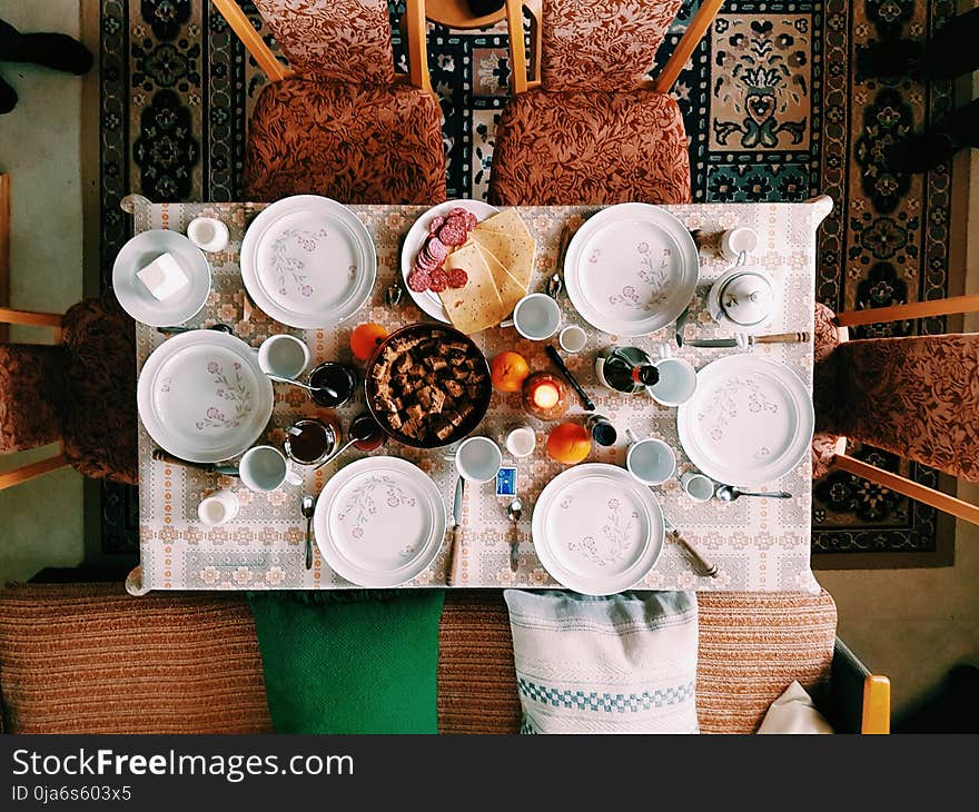 High Angle Photography of Dinner Set on Table Surrounded With Padded Chairs