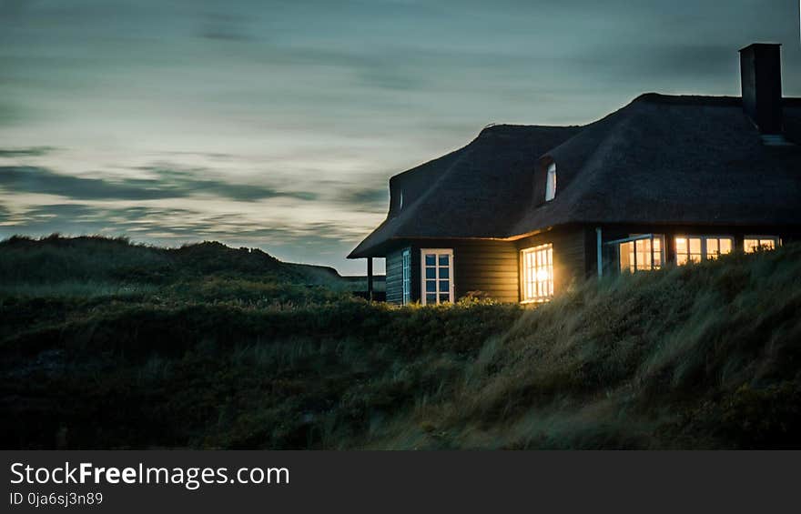 Gray House With Fireplace Surrounded by Grass Under White and Gray Cloudy Sky