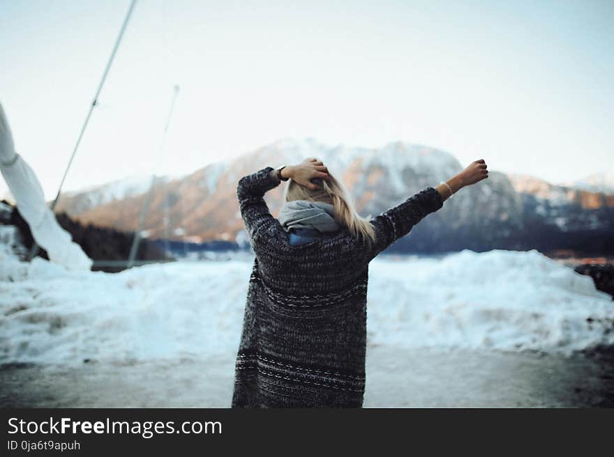 Woman in Gray and Black Tribal Cardigan Standing in Front of Snow Fields