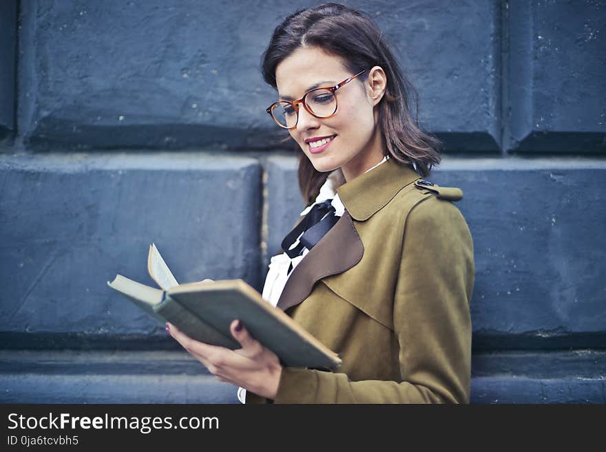 Woman In Brown Suede Peacoat Reading A Book