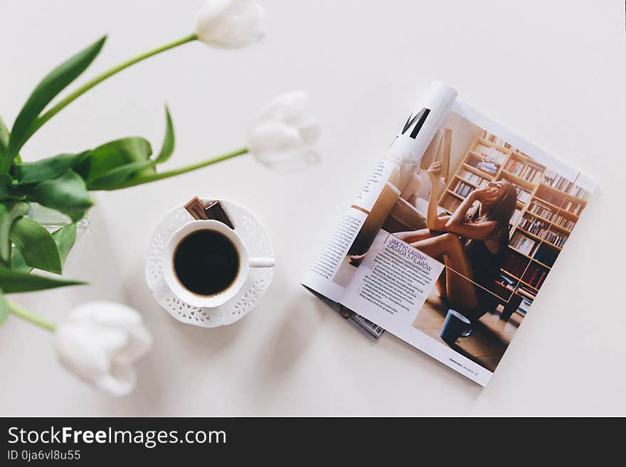 1 Teacup With Saucer and Magazine on White Surface