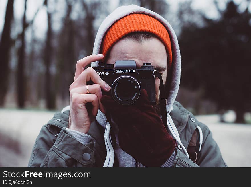 Man Wearing Gray Hooded Jacket Holding Black Camera