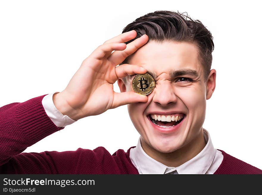 Close up of a joyful screaming businessman holding bitcoin at his face isolated over white background