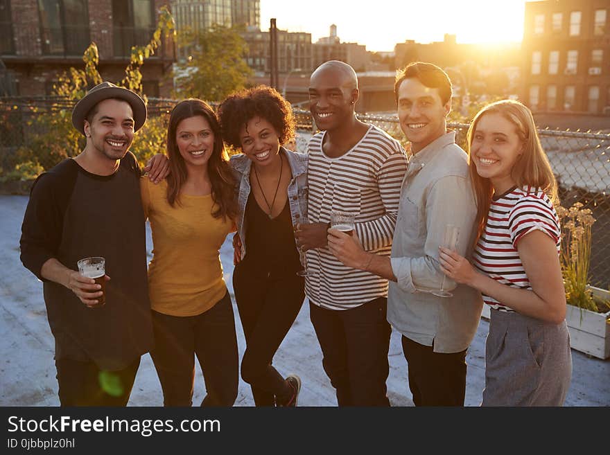 Friends at a rooftop party in Brooklyn smiling to camera