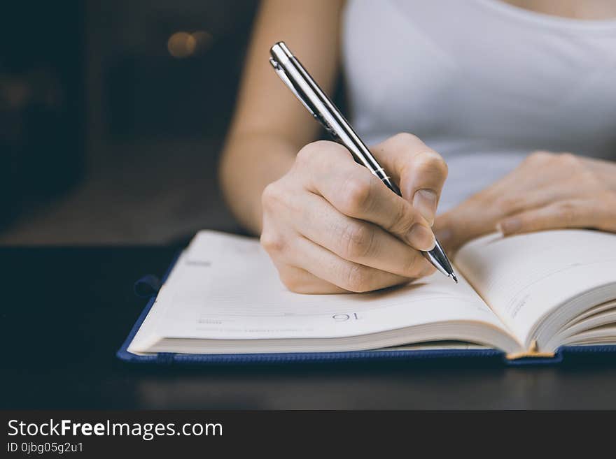 Photo of Person Writing on Notebook