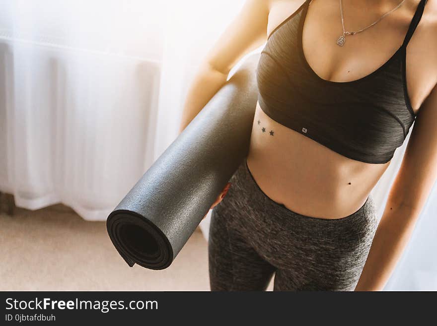 Woman in Black Sports Bra With Grey Leggings Carrying Yoga Mat