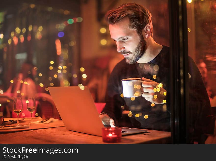 Man Holding Mug in Front of Laptop