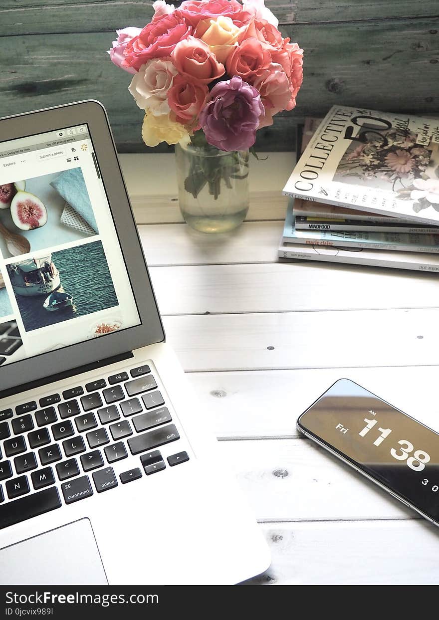 Macbook Air, Flower Bouquet and Magazines on White Table