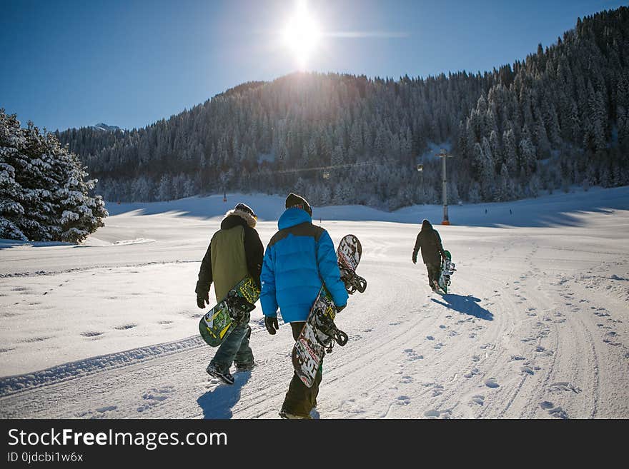 Three Person Holding Bubble Jacket Carrying Snowboards