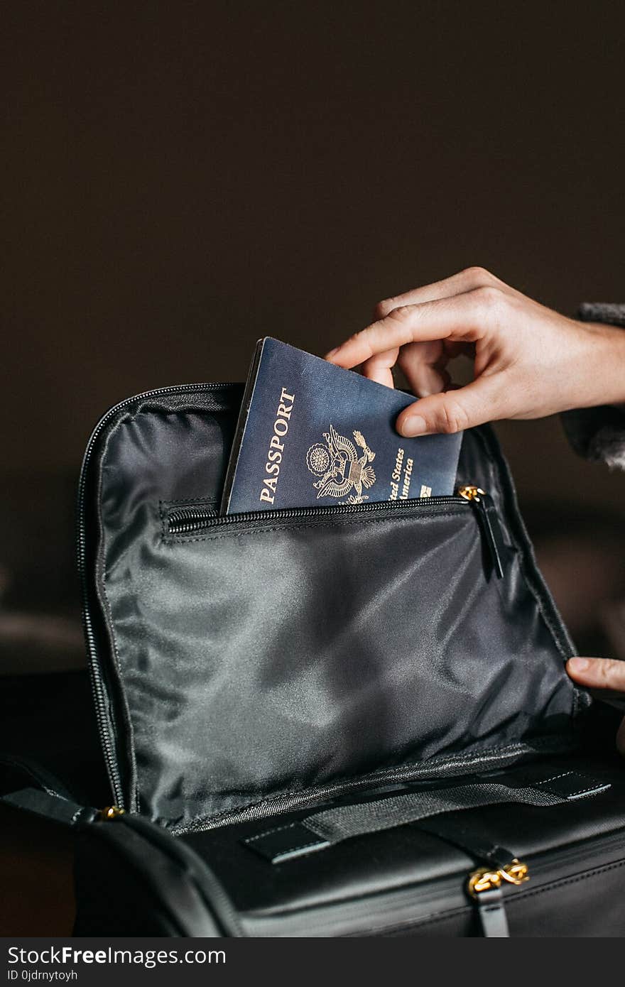 Person Putting a Passport on Bag