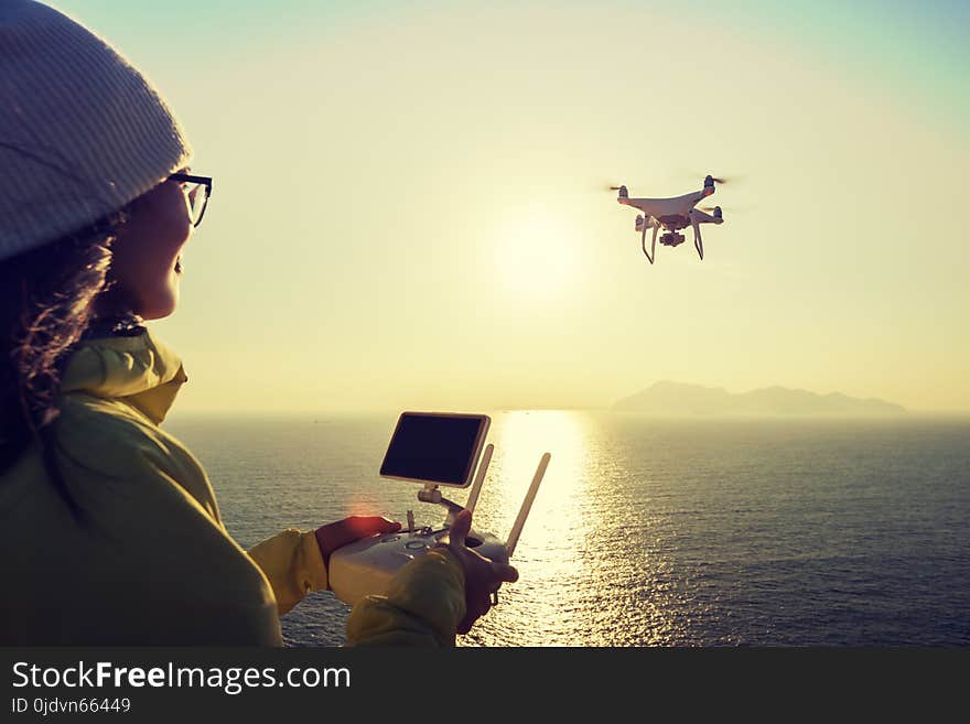 Remote control a flying drone which taking photo over sunrise sea