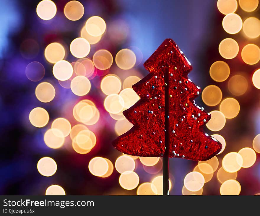 Red lollipop in the form of a New Year tree against the backdrop of garland lights. Red lollipop in the form of a New Year tree against the backdrop of garland lights.