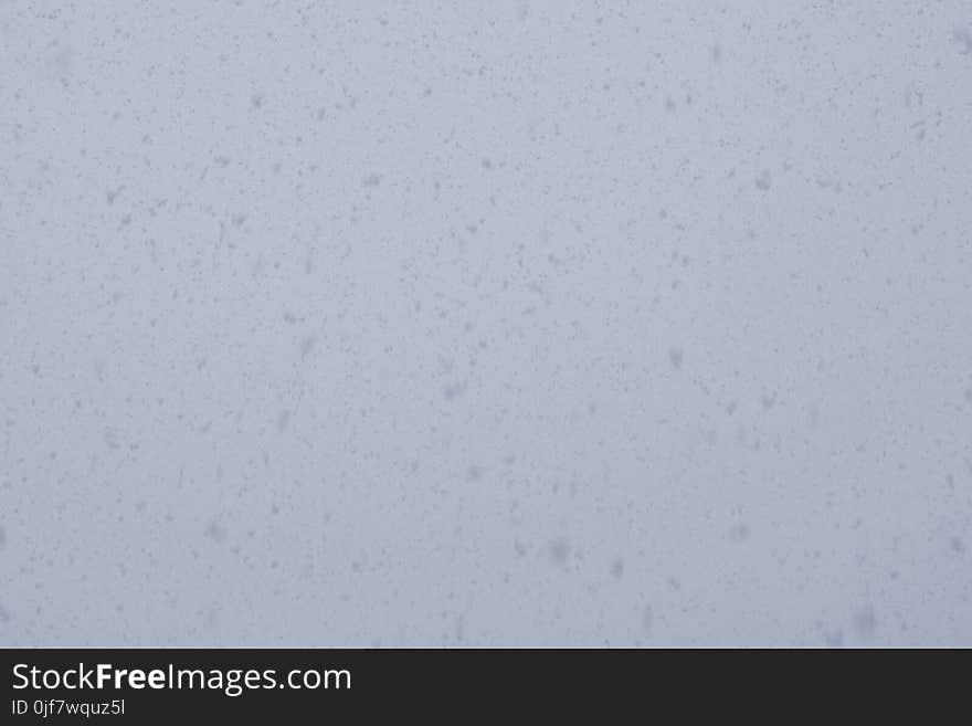 Fresh falling snow over grey sky close up background. Fresh falling snow over grey sky close up background.