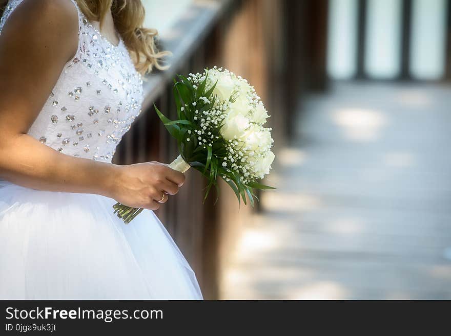 Close view of beautiful wedding bouquet with white roses in a hand of a bride (soft focus). Close view of beautiful wedding bouquet with white roses in a hand of a bride (soft focus).