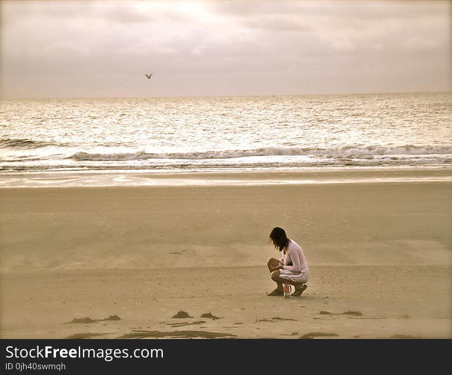 Woman in Pink Cardigan Sitting on Seashore