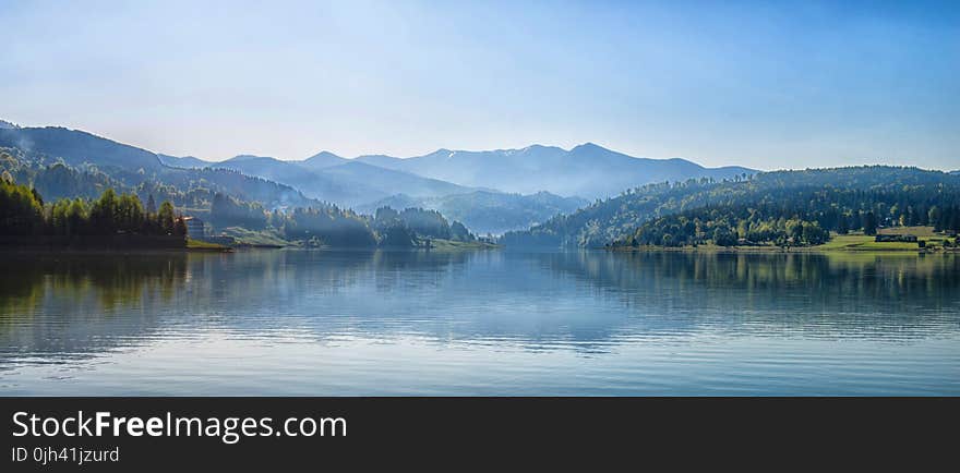 Body of Water Next to Mountain during Day Time