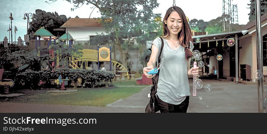 Woman Wearing Gray V Neck Cap Sleeve Top Making Bubbles