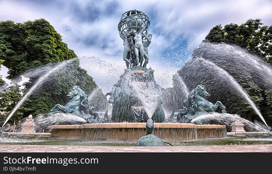 Blue Concrete Water Fountain Near Green Trees Under White Clouds