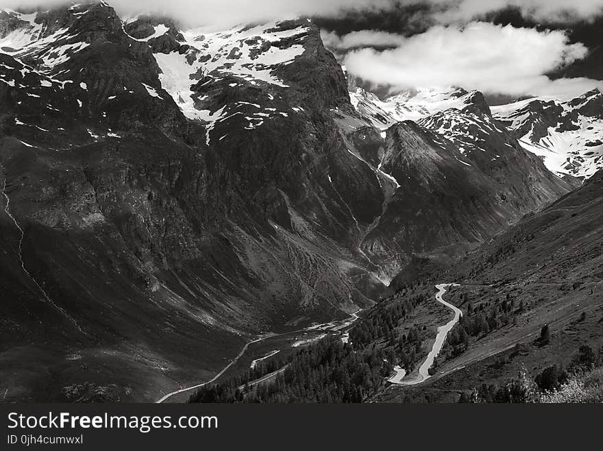 Greyscale Photo of Mountains Surrounded by Clouds