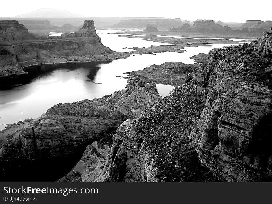 Grayscale Photography of High Rise Rock Near Body of Water