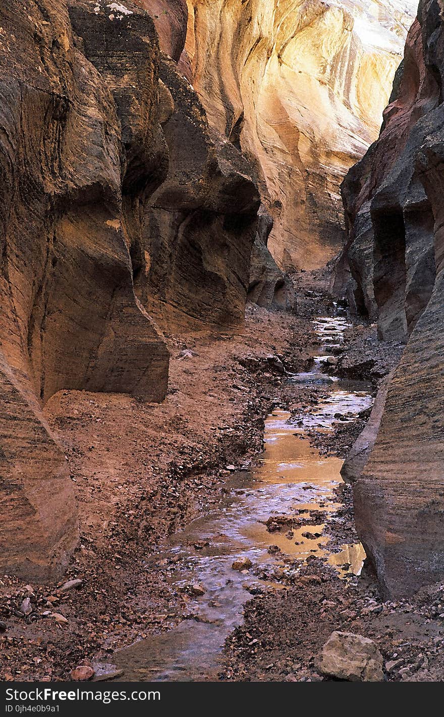 Close Up Photo of Black Rock Formation With Litter Amount of River in the Middle of Valley