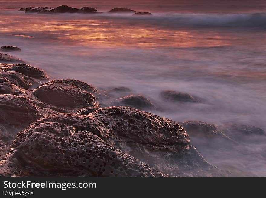 Brown and Black Rock Formations With Fog during Sunset