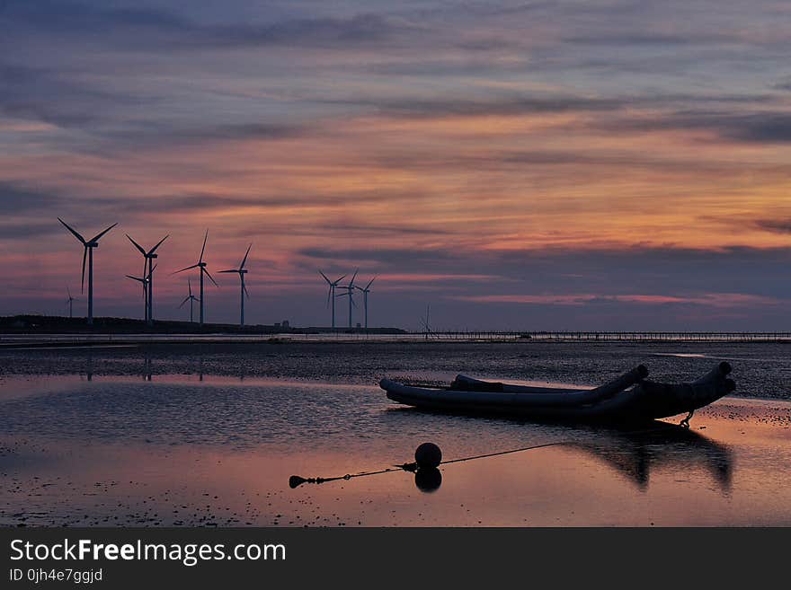 Windmills Behind Canoe Boat during Sunset