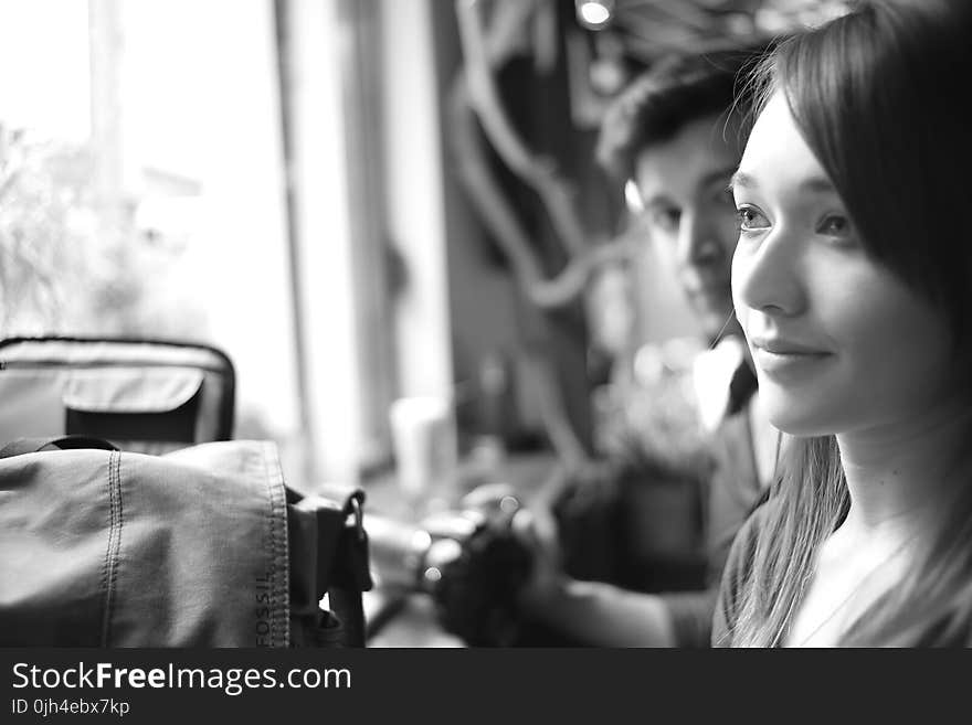 Grayscale Photo of a Woman Being Stared by a Man Inside a Room