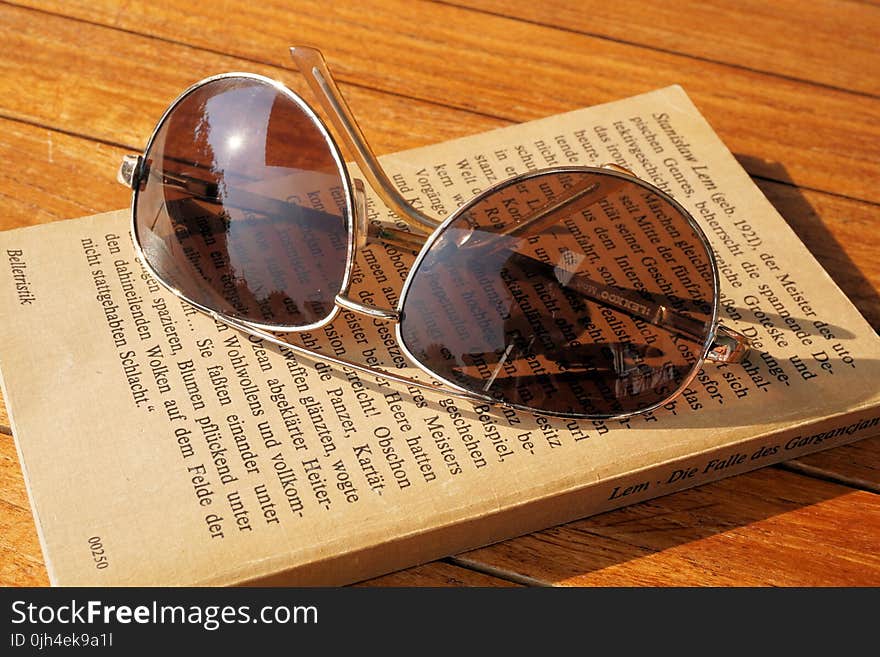 Silver Steel Framed Aviator Sunglasses on Top of Book during Daytime