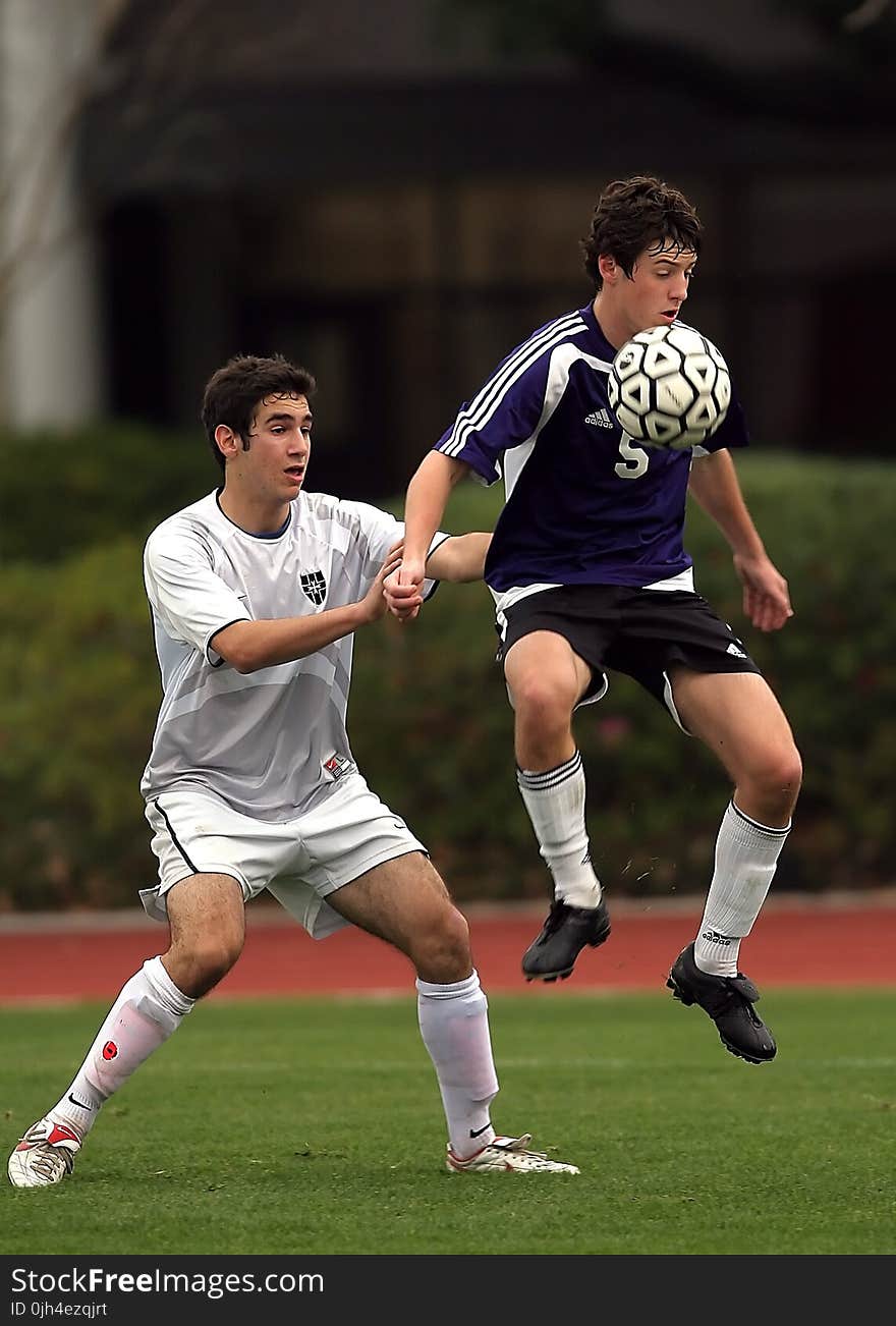 Two Men Playing Soccer at Soccer Field Near Green Plants during Daytime