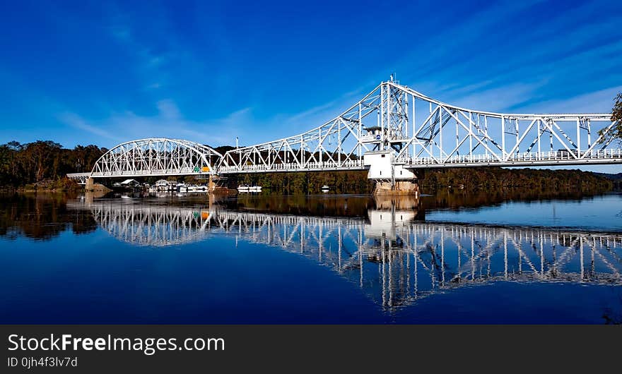 White Bridge Above Body of Water Creating a Reflection Under White Clouds