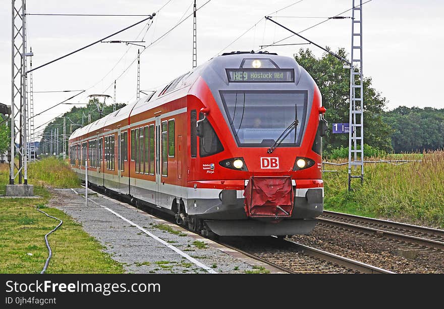 Red Train on Tracks With Green Grass Beside Under Bright Sky