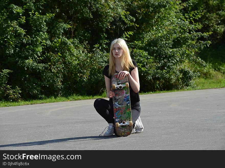 Woman in Black Shirt and Pants Holding Skateboard during Daytime