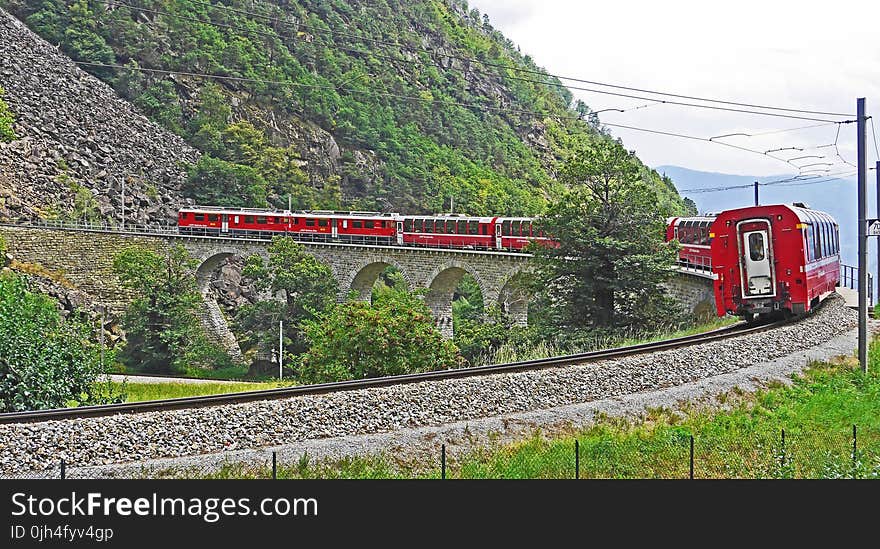 Red Train on Black Steel Train Rail during Day