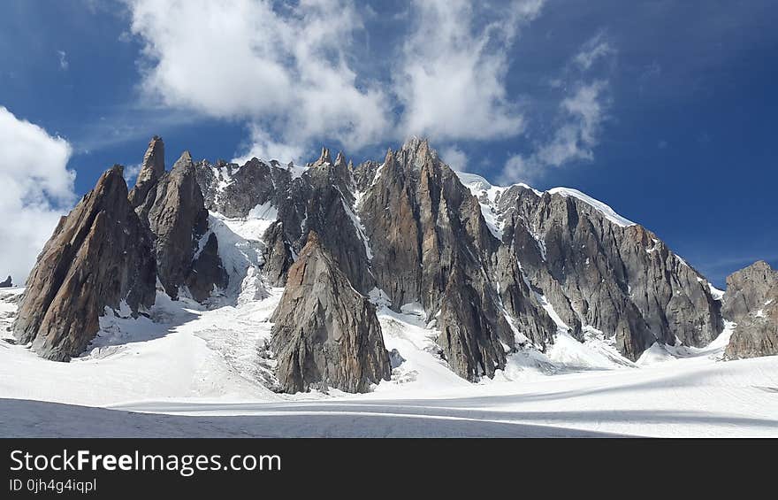 Rock Mountain Covered With Snow Under Blue Sky at Daytime