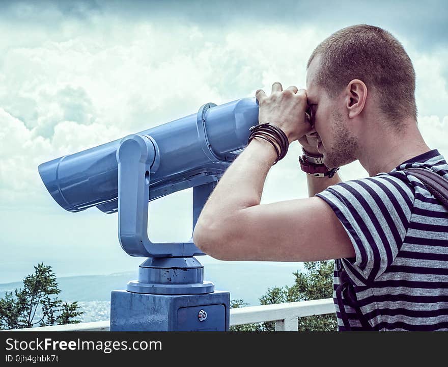 Person in White and Gray Stripes Crew Neck T Shit Using Telescope Near White Metal Handrails Under White Clouds during Daytime