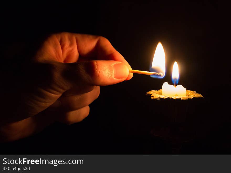 Person Holding Match Stick With Fire in Front of Candle With Fire