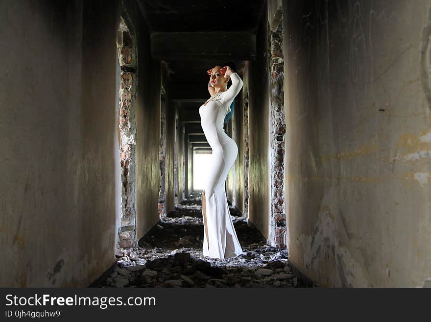 Woman in White Bodycon Maxi Dress Posting in Between White Concrete Wall