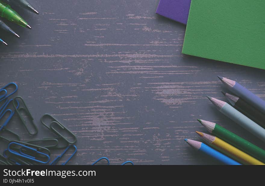 Colored Pencils on a Gray Desk With Paper Clips and Folders