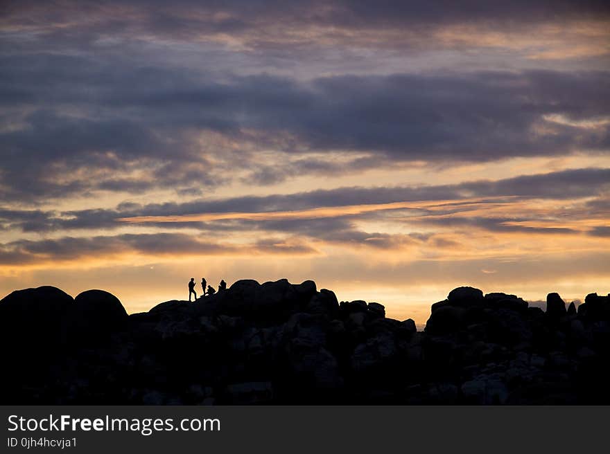 Silhouette of 4 Persons Resting on Top on Mountain during Dusk