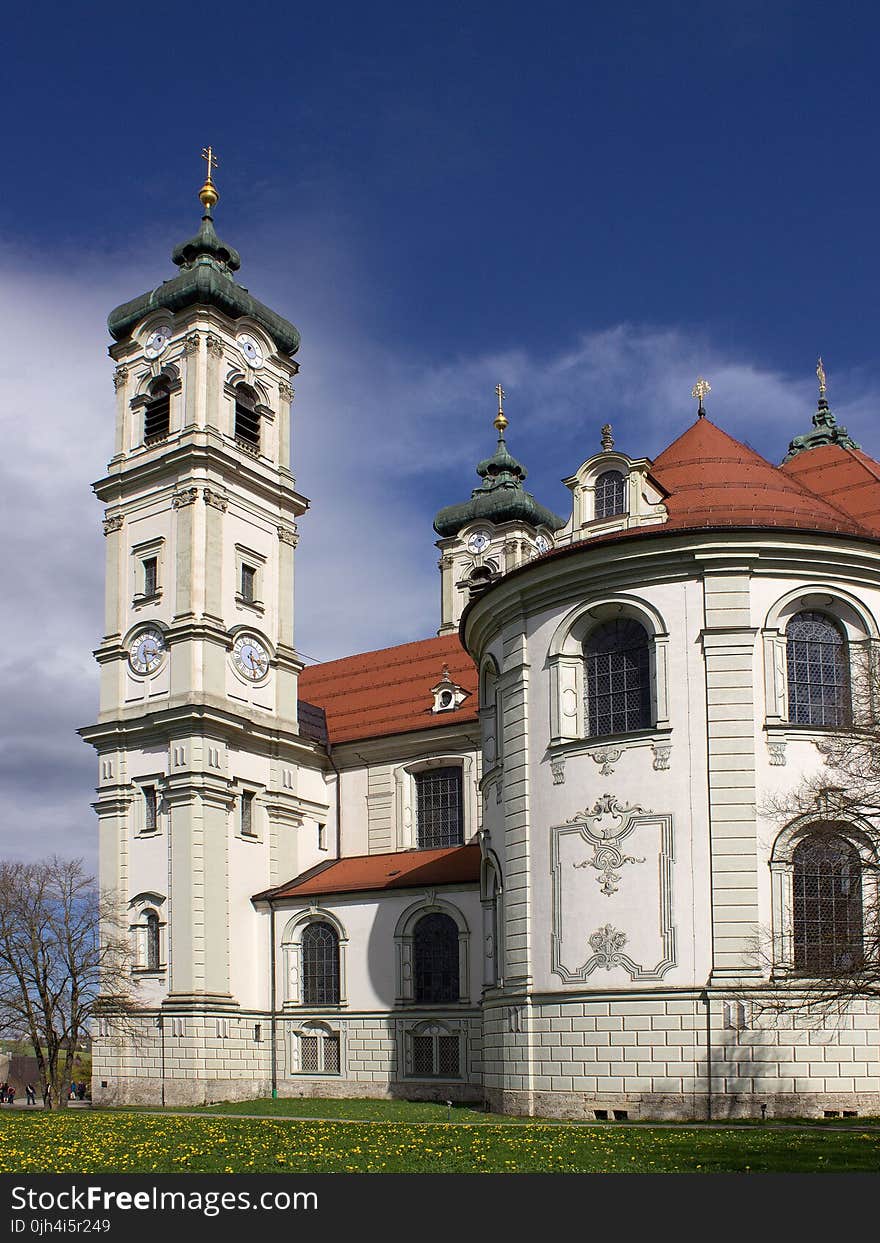 White and Orange Painted Building With Tower Near Leafless Tree Under White Clouds and Blue Sky